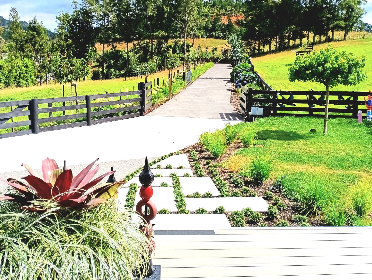 A garden path winding past sculptures and lawns toward the gallery deck at White House Collectables